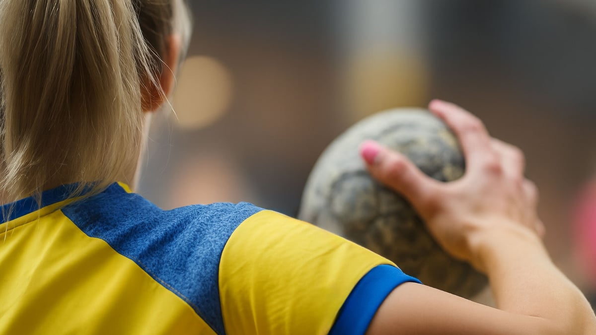 En handbollsspelare håller upp en boll och gör sig redo för att kasta den.