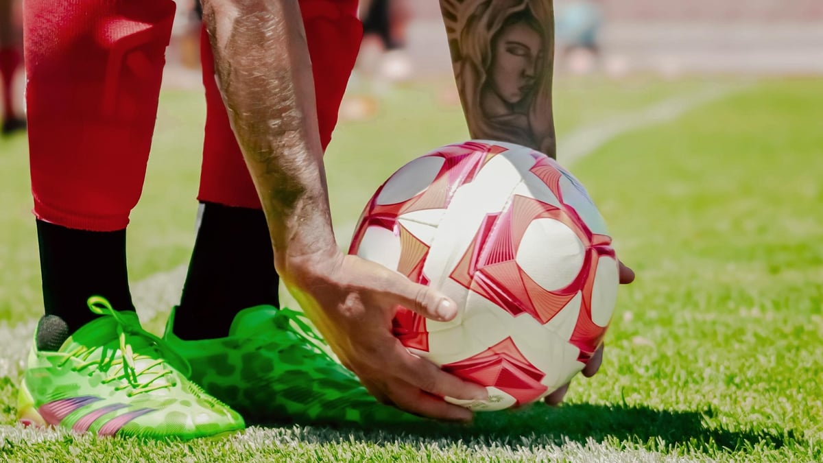 En spelare böjer sig ner för att lägga upp en fotboll inför en utspark.