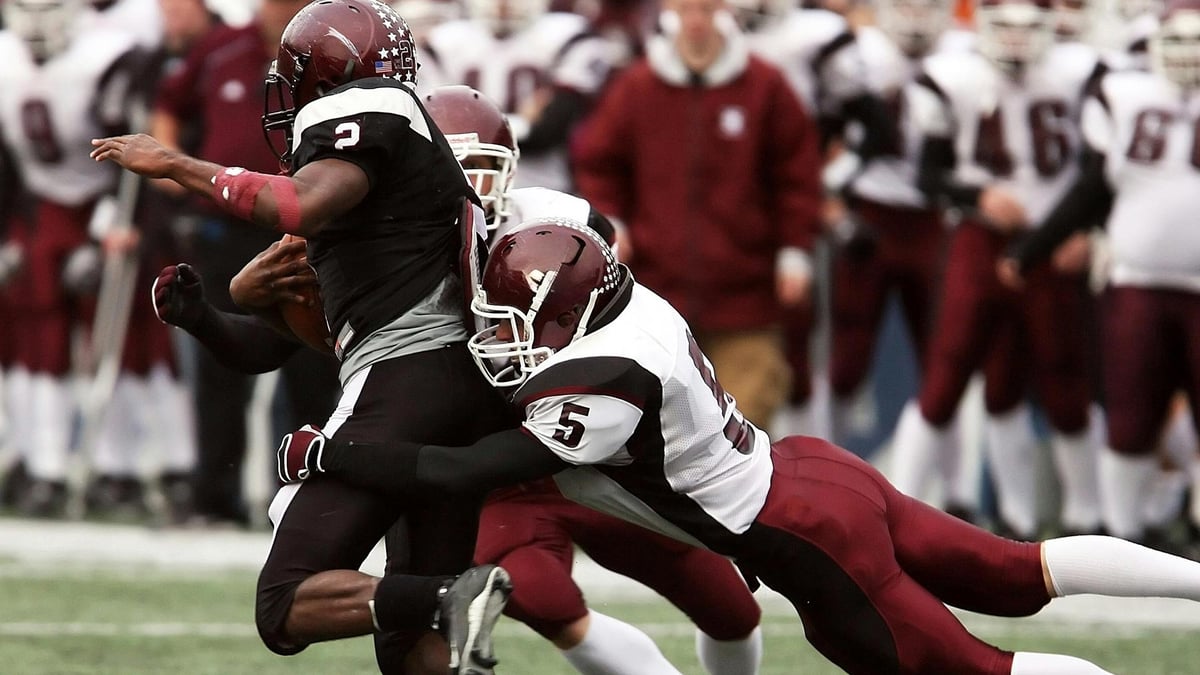 Två spelare tacklar en motspelare i amerikansk fotboll.