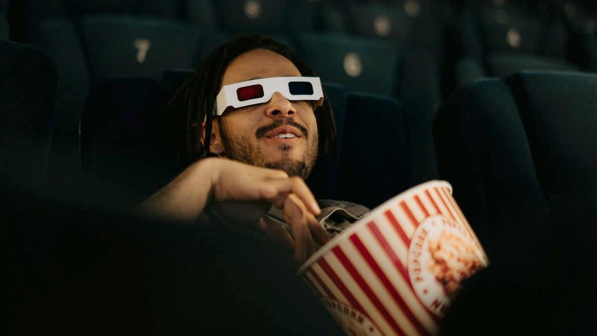 En person kollar på en film med Stellan Skarsgård i en biograf och äter popcorn.